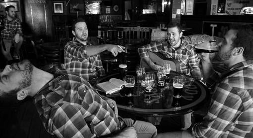 A man in a plaid shirt appears multiple times at a pub table, laughing, pointing, playing guitar, drinking beer, and leaning back dramatically, surrounded by drinks in a lively bar setting.