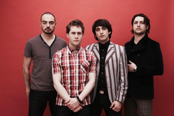 Five young men stand in a row against a red background, dressed in stylish casual and semi-formal clothing, with the band name FOR THE FOXES written across the bottom.