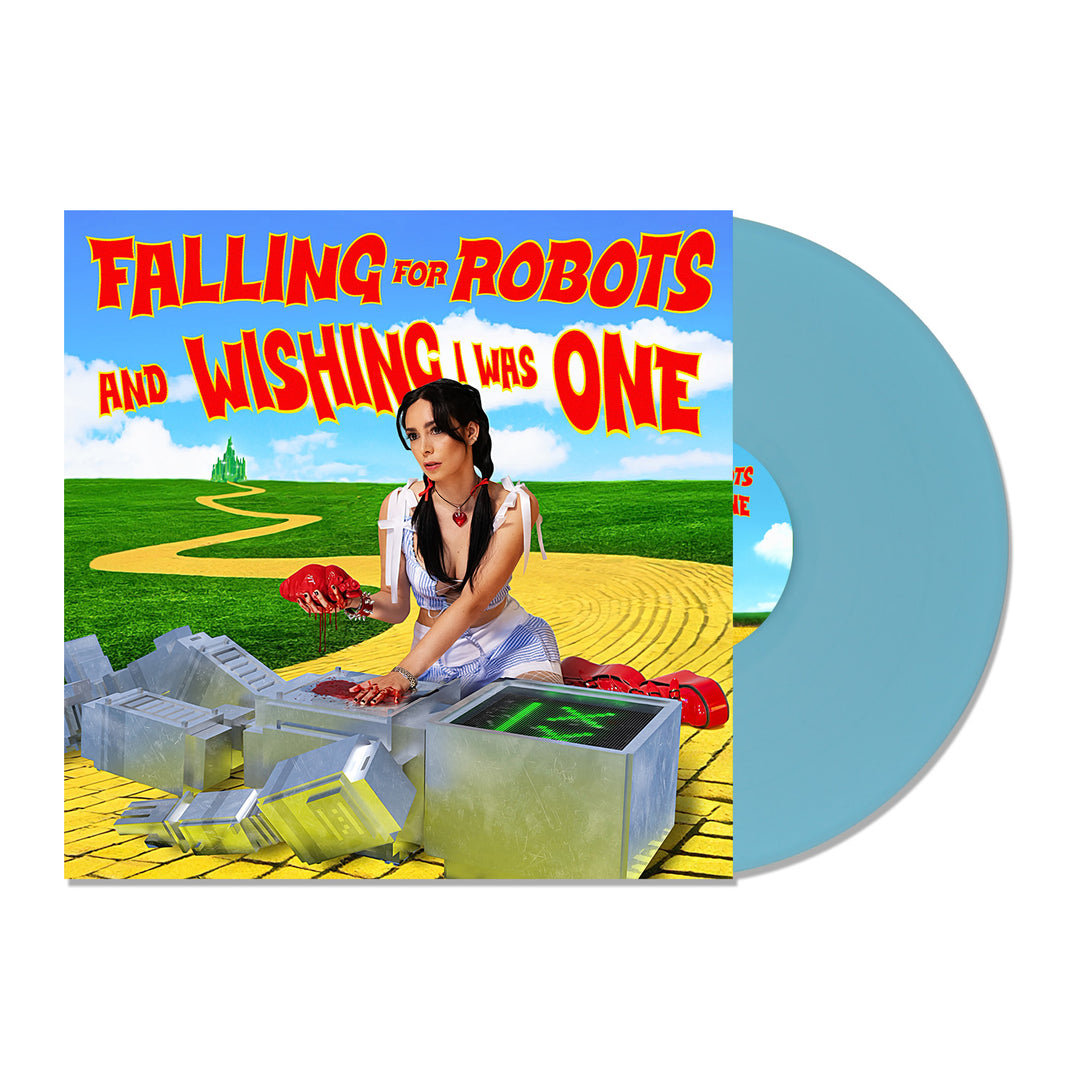 L0L0 album cover features a woman as Dorothy from The Wizard of Oz on a yellow brick road assembling a robot, with a blue vinyl beside her. Text: “Falling for Robots and Wishing I Was One.” Limited edition release.