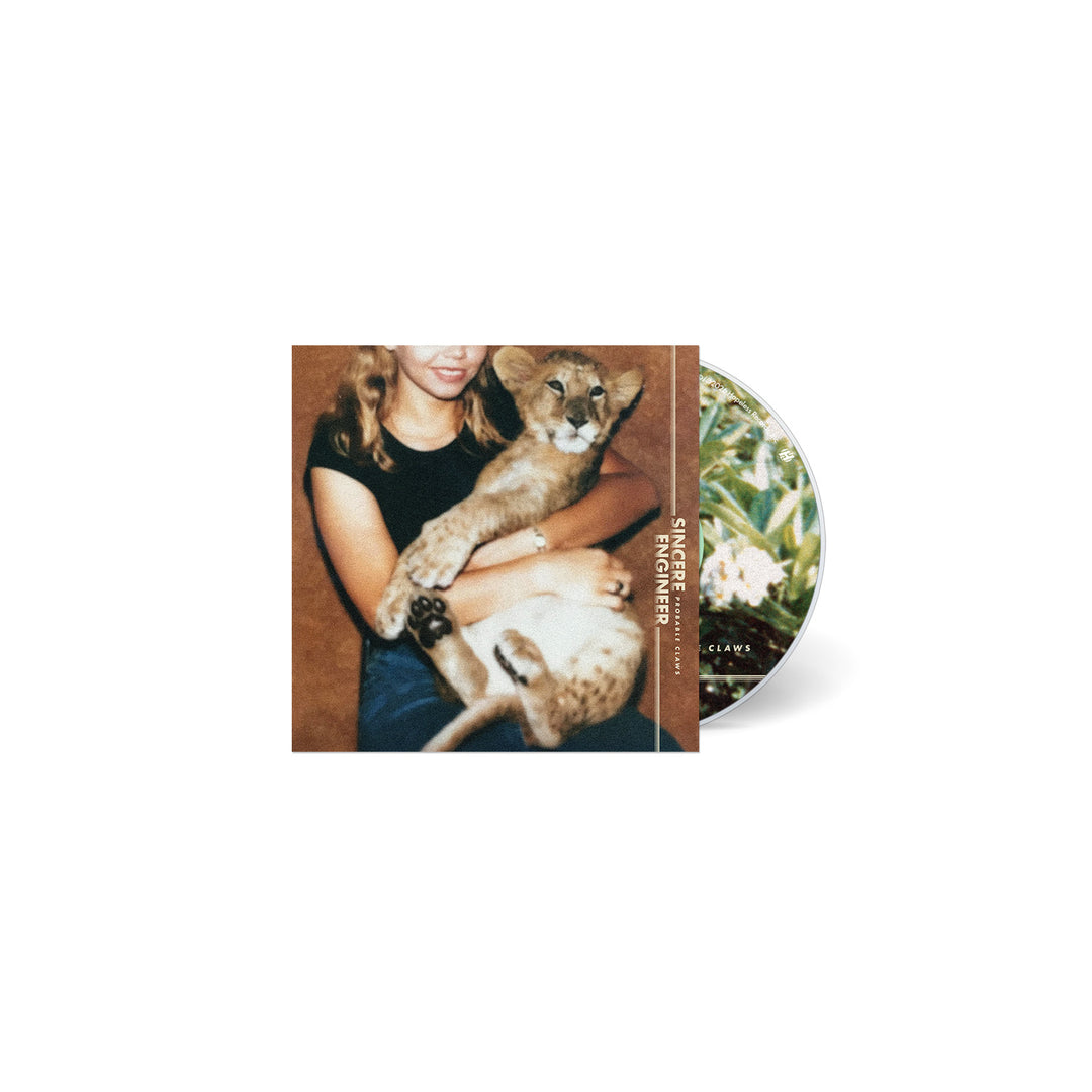 A CD by Sincere Engineer with a cover of a smiling young woman in a black shirt holding a lion cub. The partially visible disc displays swirling, vividly colored hallucinogenic flowers and foliage.