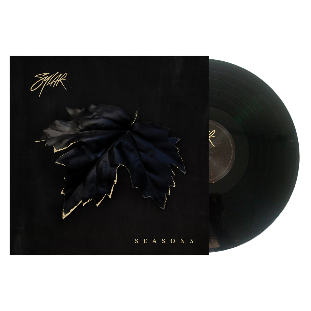 A vinyl record partially slides out of its cover. The Sylar album artwork displays a large black leaf with gold edges on a dark background, SYLAR in stylized text at the top left, and SEASONS in gold letters at the bottom.