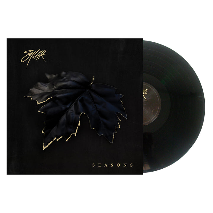 A vinyl record partially slides out of its cover. The Sylar album artwork displays a large black leaf with gold edges on a dark background, SYLAR in stylized text at the top left, and SEASONS in gold letters at the bottom.