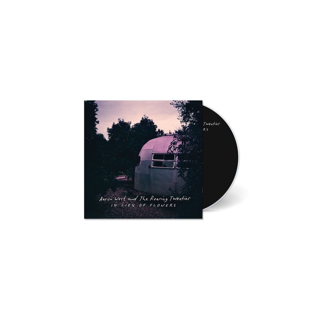 A CD case and disc for In a Week of Flowers by Aaron West and the Roaring Twenties, featuring dusk trees, a trailer, handwritten-style white text, and subtle Roman Candles references on the cover.