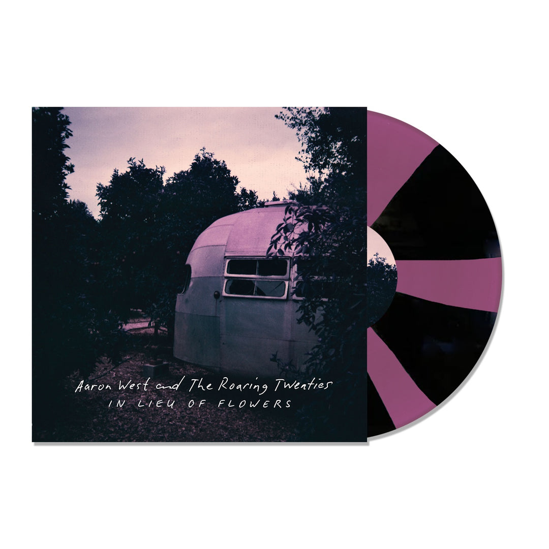 The album cover for In Lieu of Flowers by Aaron West and the Roaring Twenties features a trailer at dusk amid trees. The semi-visible Purple/Black Pinwheel Vinyl creates a striking spiral pattern in the scene.