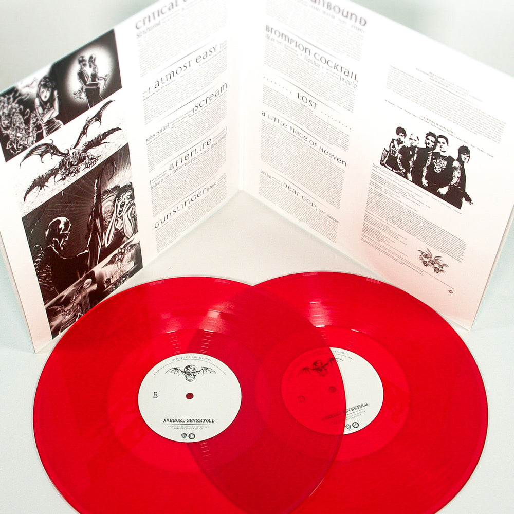 Two translucent red vinyl 2XLP records from Avenged Sevenfold lie in front of an open self-titled album gatefold featuring black and white band photos, song lyrics, and liner notes.