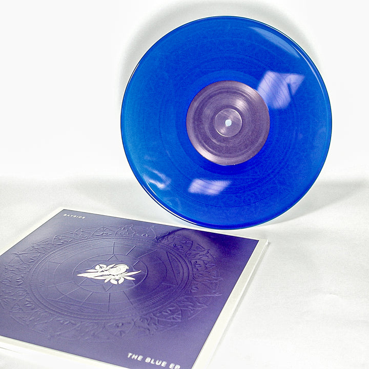 Vinyl album cover for Bayside "The Blue EP" on a white background. Cover is Blue with a Mandala. White bird on a flower centered. White Text in the corners "Bayside" &amp; "The Blue EP". Vinyl is Transparent Blue.