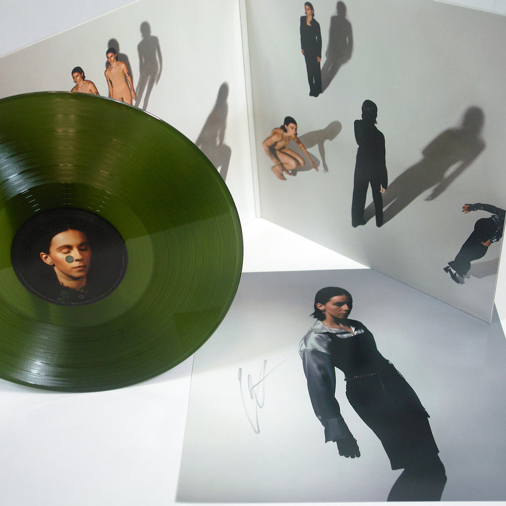 A green PVRIS vinyl record sits beside its open album cover, a signed 12x12 insert, and the tracklisting. Both the cover and insert feature artistic photos of a person posing with bold shadows on a white background.