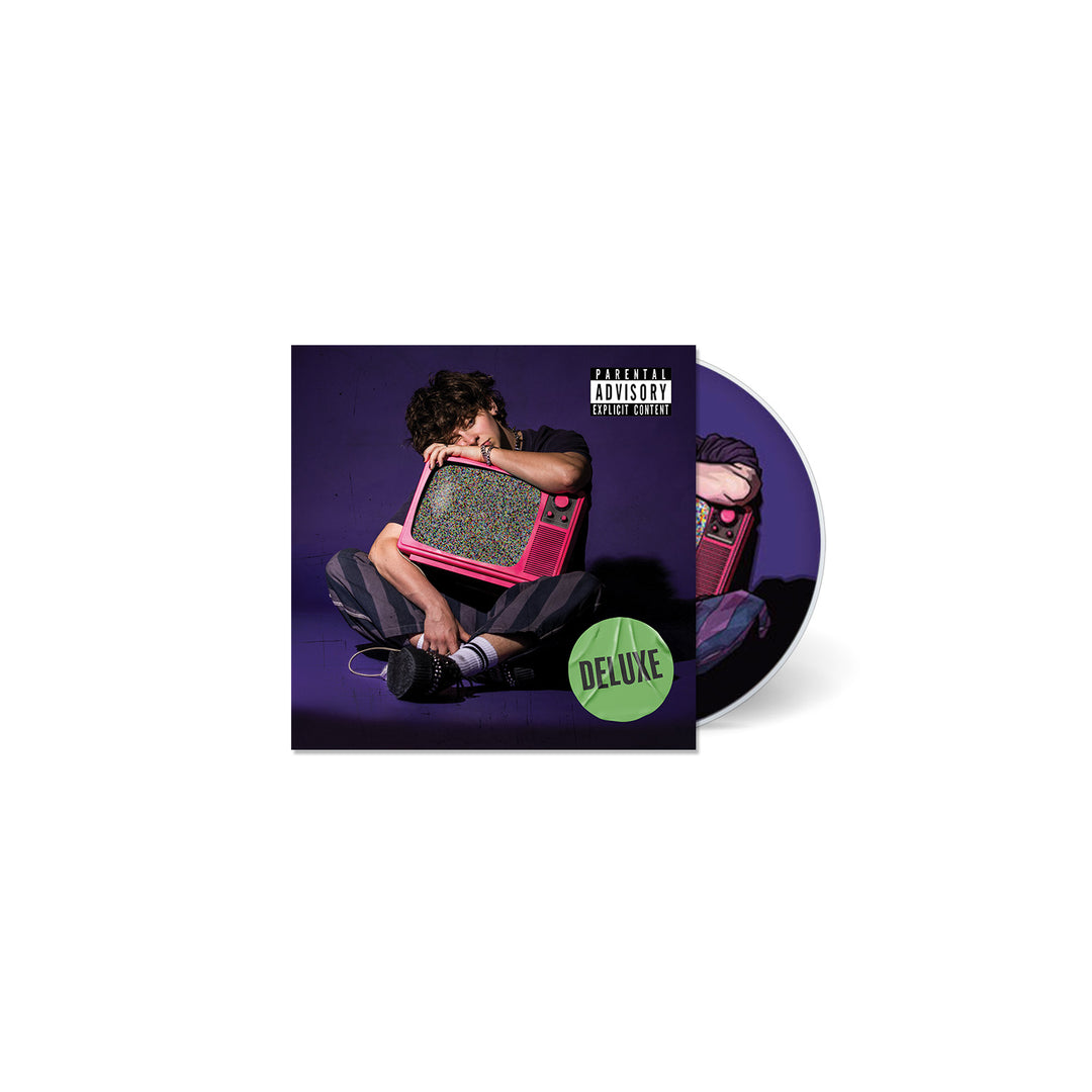 A person sits on the floor holding a pink retro TV, as seen on NOAHFINNCE’s GROWING UP ON THE INTERNET album cover, with a Deluxe green sticker, parental advisory label, and the CD visible behind.