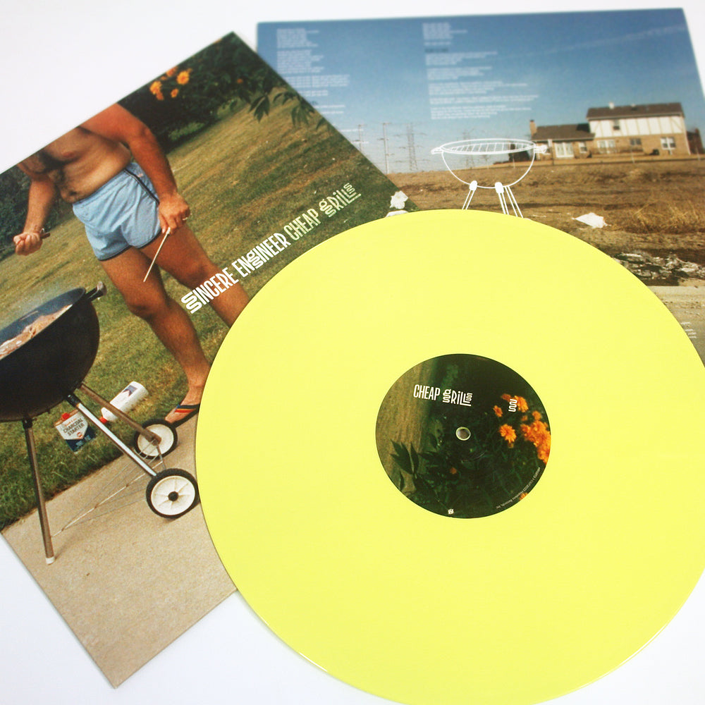 A yellow LP labeled Cheap Grills rests atop two album covers—one with a shorts-clad barbecuer, the other with a grill and suburban house—perfectly capturing the Sincere Engineer brand’s vibe.