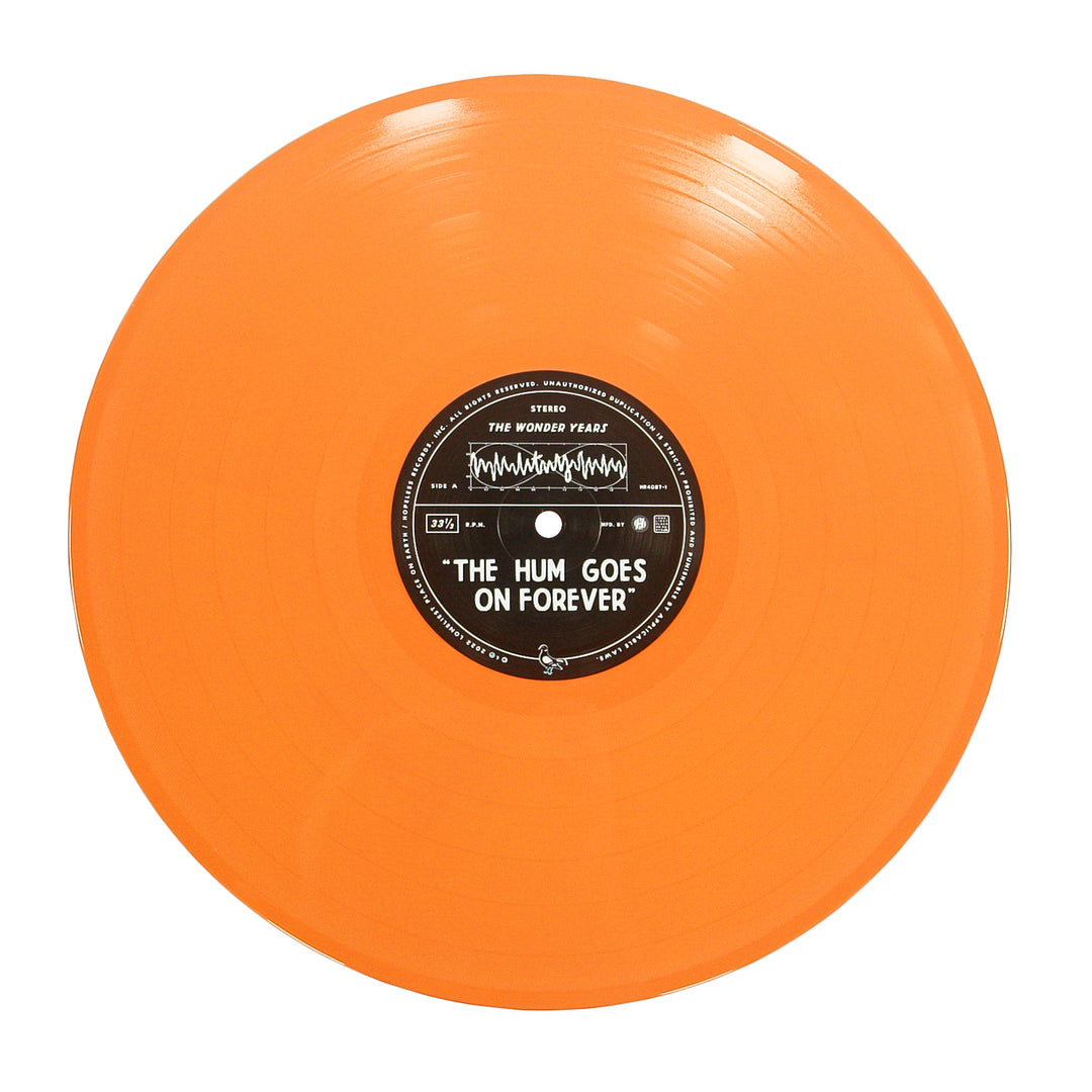 An orange vinyl album by The Wonder Years with a black center label that reads THE HUM GOES ON FOREVER, featuring bold sound wave graphics.