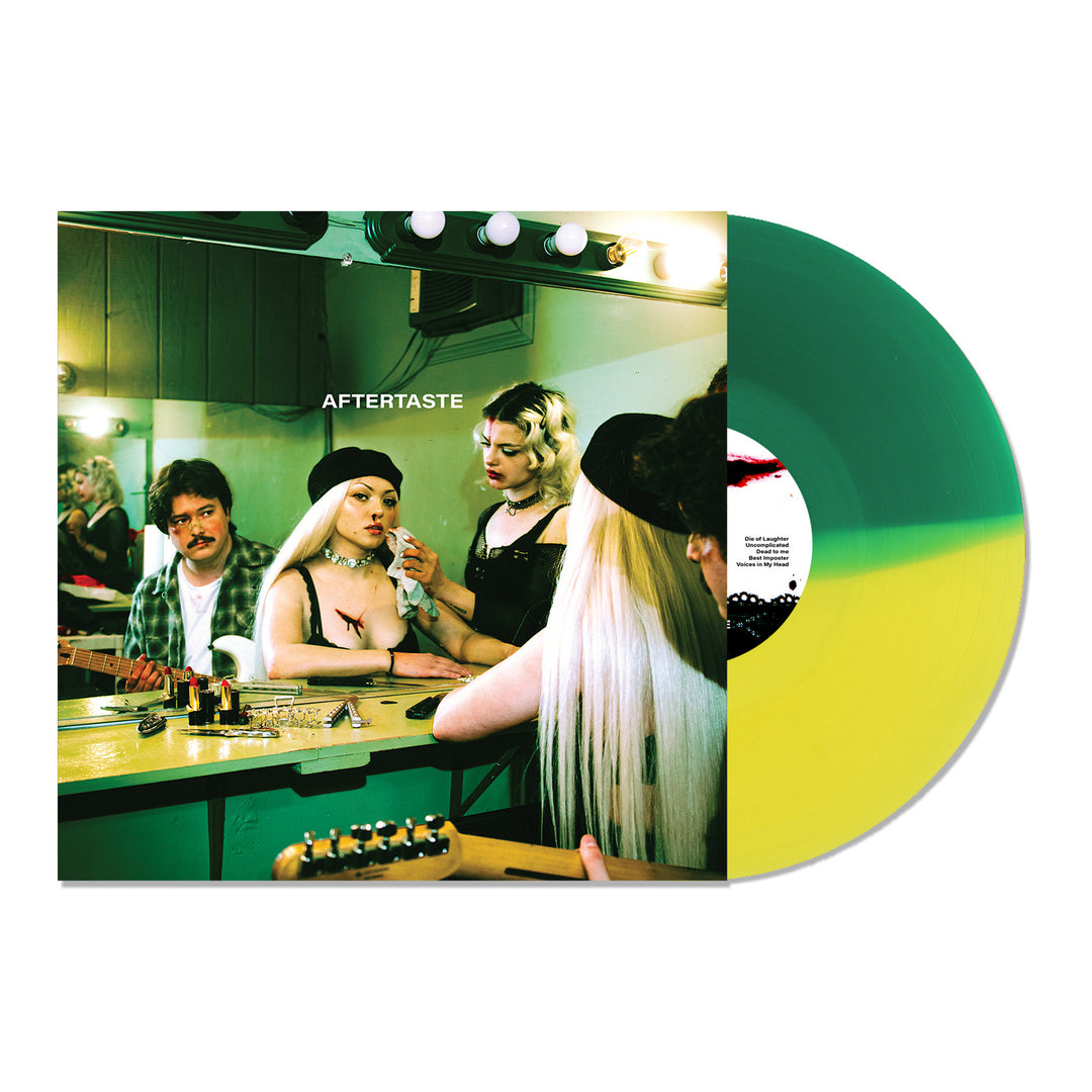 A Limited Edition Green & Yellow Split LP partially covers an album by Hey Violet, featuring three people in a backstage dressing room with AFTERTASTE written on the mirror above their reflections.