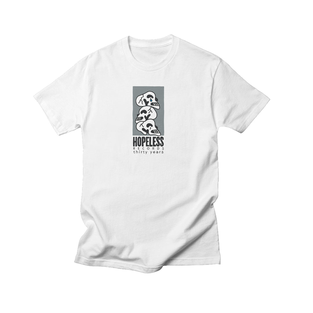 A white Comfort Colors t-shirt from Hopeless Records featuring a modern black and white graphic of three dinosaur skulls stacked above HOPELESS thirty years. Minimalist design—ideal for unique apparel enthusiasts.