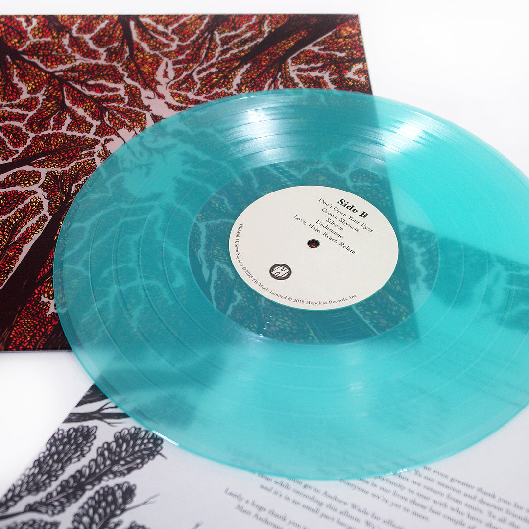 A translucent turquoise vinyl record labeled Side B rests on its colorful abstract album cover for Crown Shyness by Trash Boat, with a partially visible black and white printed insert underneath.
