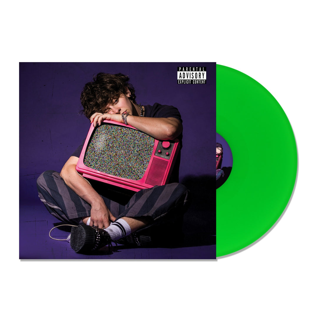 A person sits on the floor holding a pink vintage TV with static, set against a purple background. A neon green limited edition NOAHFINNCE vinyl with a parental advisory label is also featured.