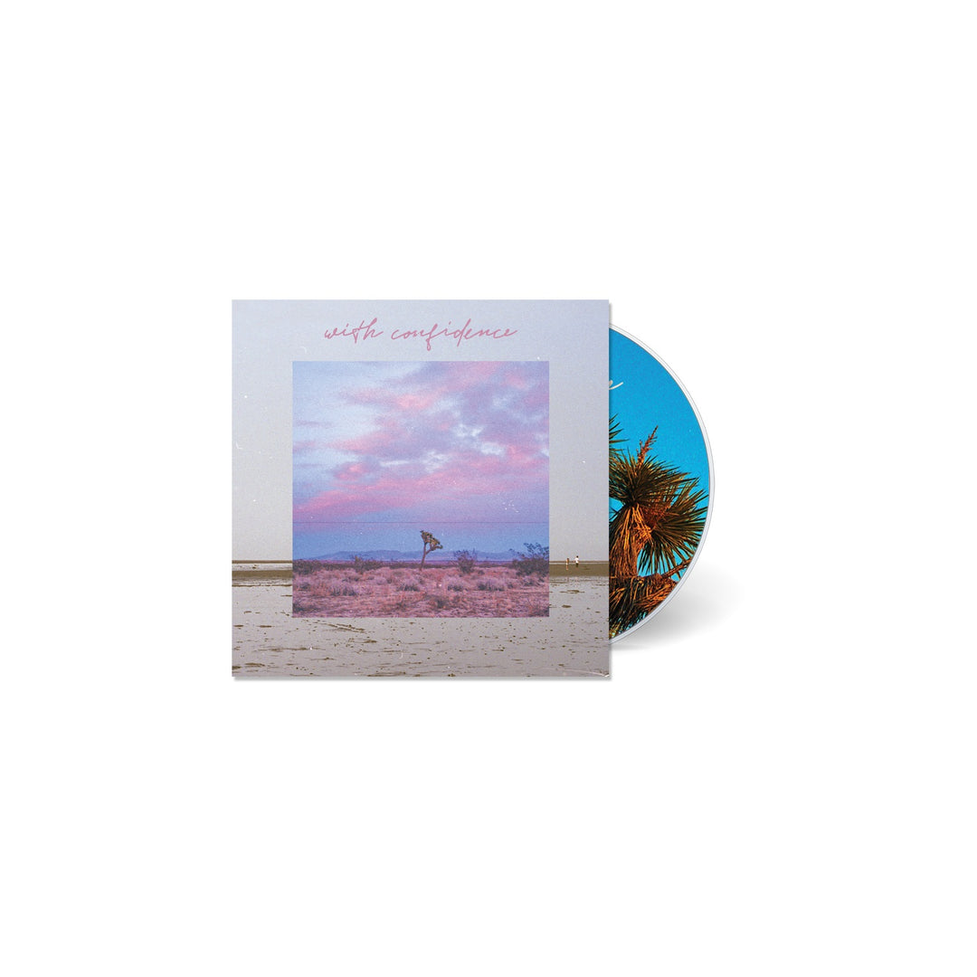 A pastel pink and purple beach scene decorates the With Confidence CD cover, with the brand name above. The partially revealed CD displays a palm tree on a blue sky background, reflecting the album’s vibrant energy.