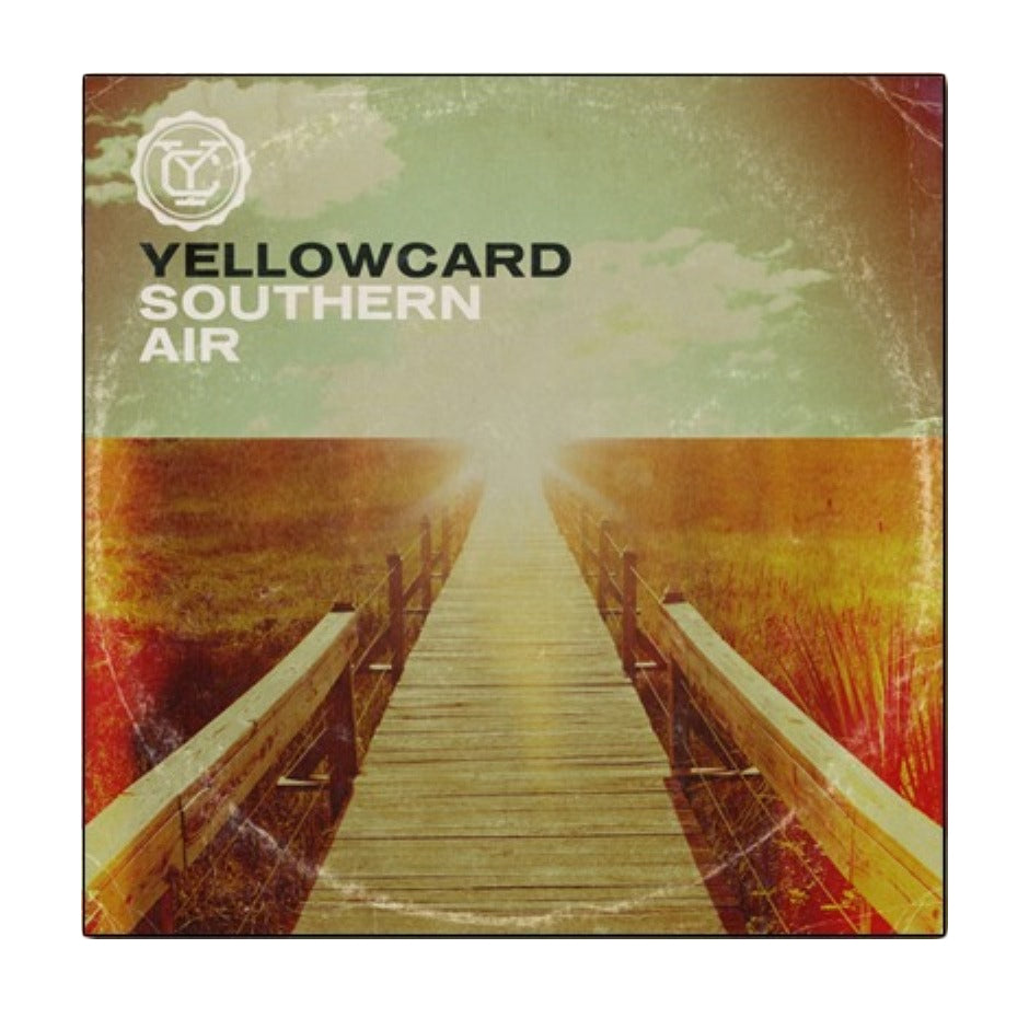 A wooden boardwalk stretches into a bright, hazy sky over grassy fields on the Yellowcard album cover, which features bold text and a vintage, weathered effect.