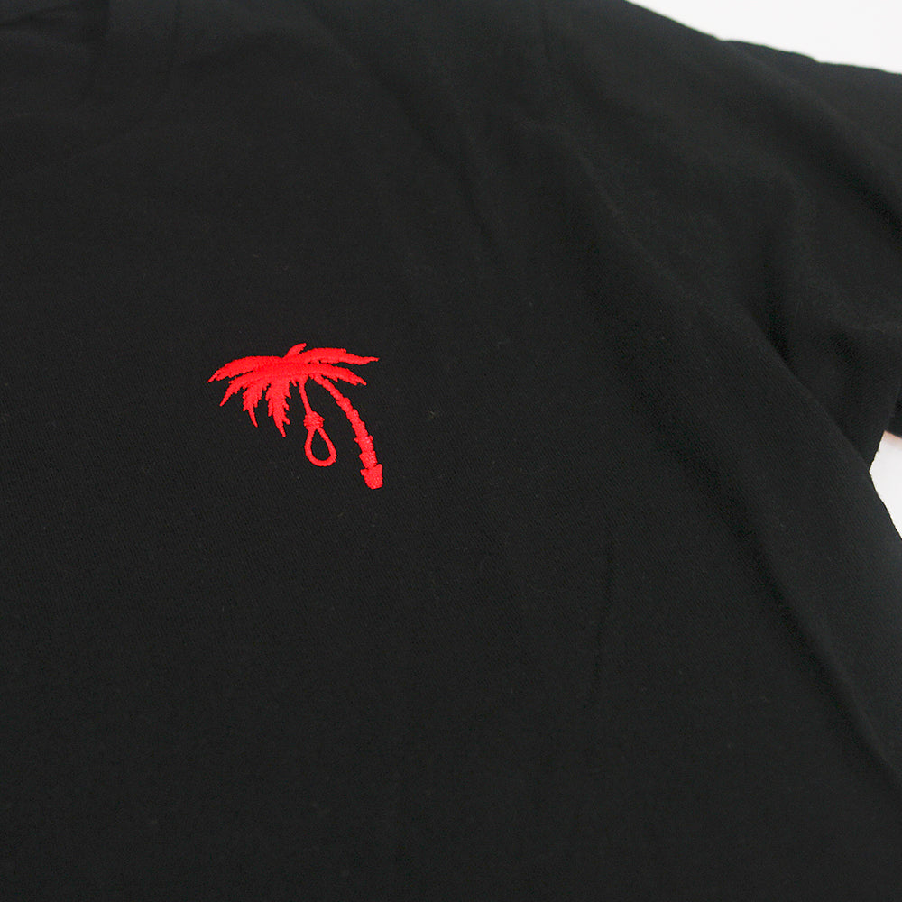 A black Trophy Eyes t-shirt featuring a small embroidered palm tree with a noose hanging from one branch on the left chest area.