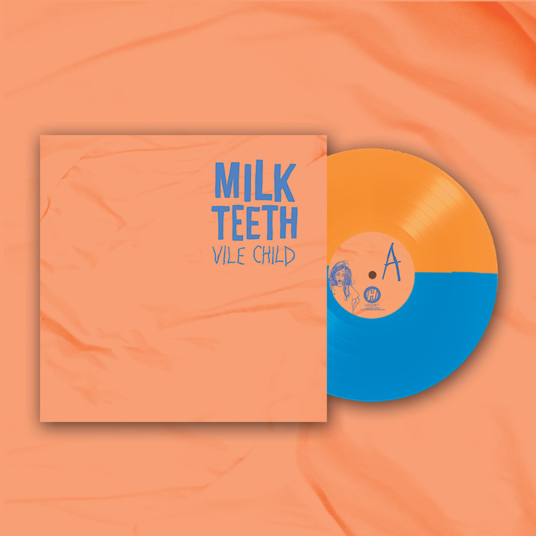 A vinyl record by Milk Teeth, half-orange and half-blue, partly in a peach sleeve with blue MILK TEETH VILE CHILD text. It rests on matching peach fabric; the opaque vinyl’s finish pairs with the bold tracklisting on the sleeve.