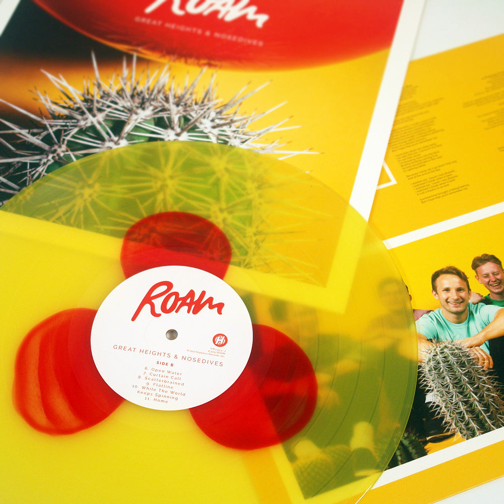 A close-up of a yellow w/ red balloons ROAM vinyl record labeled Great Heights & Nosedives sits on its colorful album cover and insert, which feature cacti imagery, smiling band members, and the tracklisting.