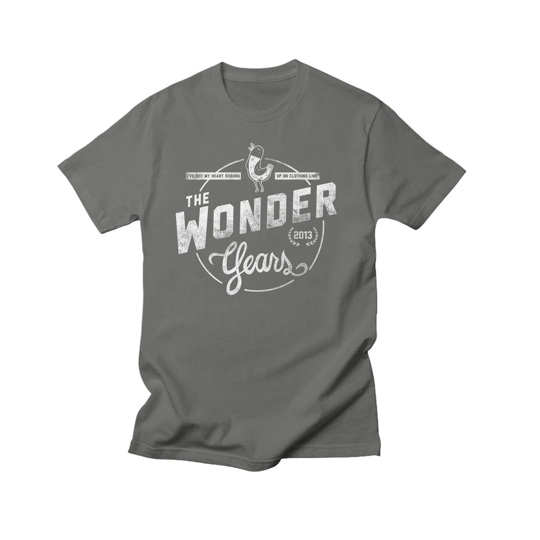 A gray Comfort Colors T-shirt by The Wonder Years with a white vintage-style circular graphic featuring a guitar, musical notes, and The Wonder Years Gears (2013) text. Made from soft ring spun cotton for comfort.