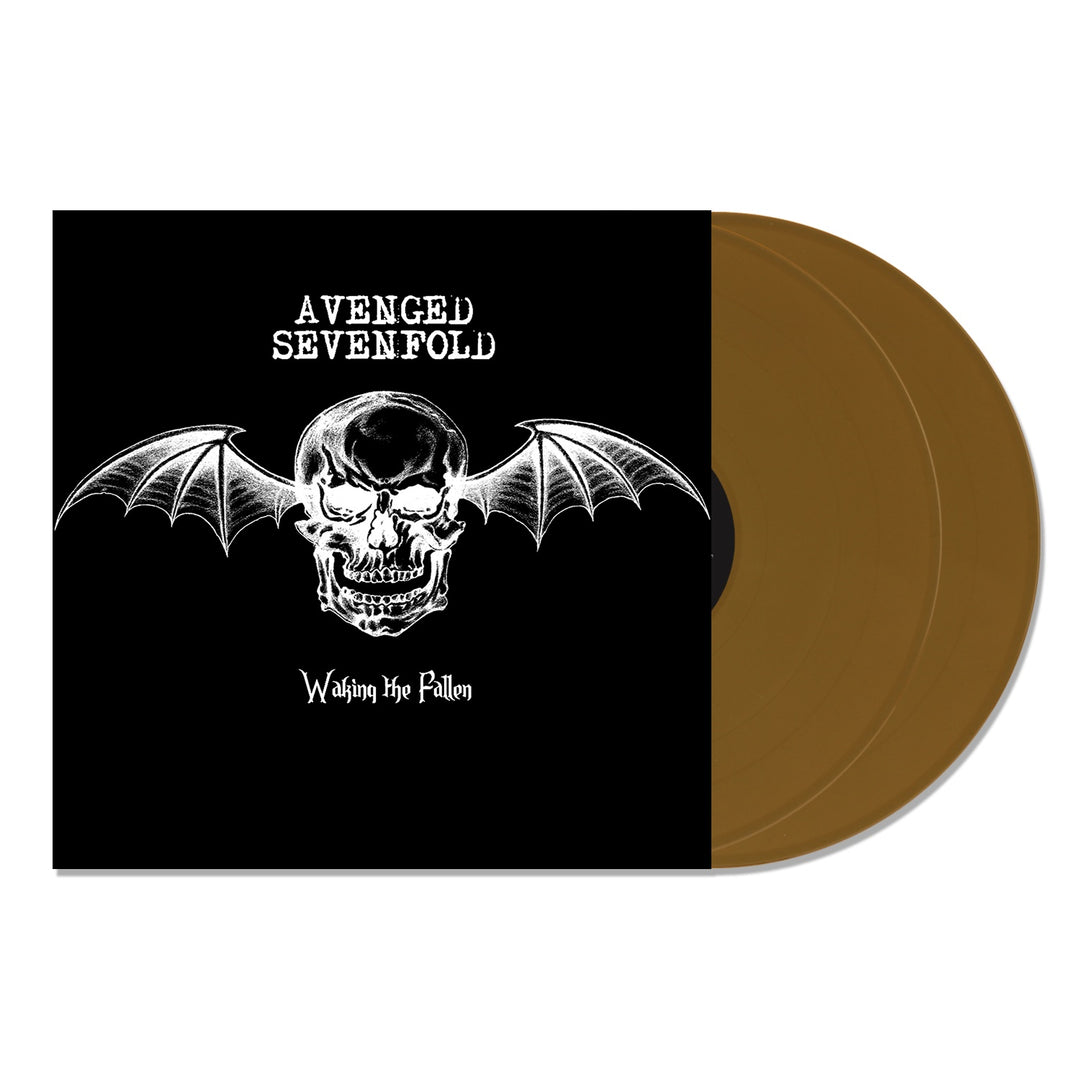 Avenged Sevenfold’s Waking the Fallen 20th Anniversary Gold 2XLP album cover shows a white bat-winged skull on black beside two gold vinyl records, with the bands name above and album title below the skull.
