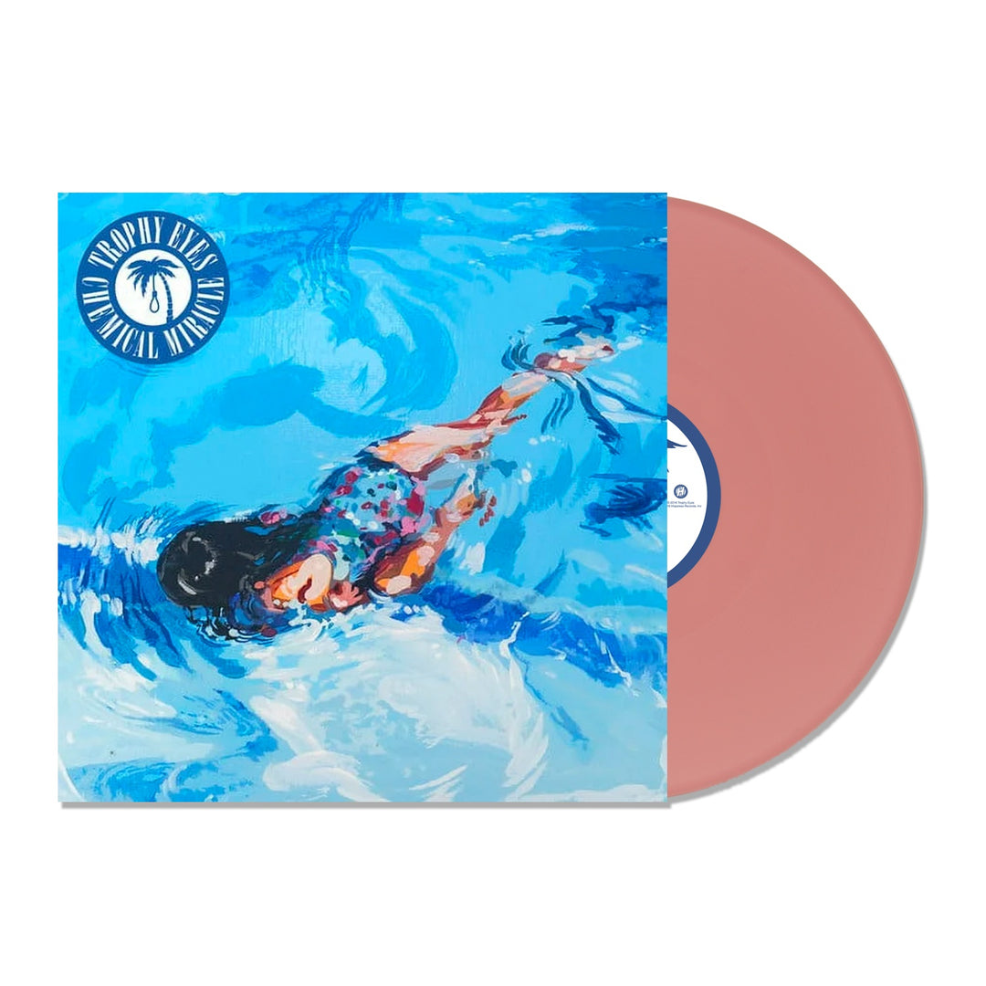 A pink vinyl record slides out of its sleeve, which shows an illustrated woman swimming underwater in blue water. The sleeve features a white palm tree logo and the text “Droppin’ Eyes Tropical Versions” by Trophy Eyes.