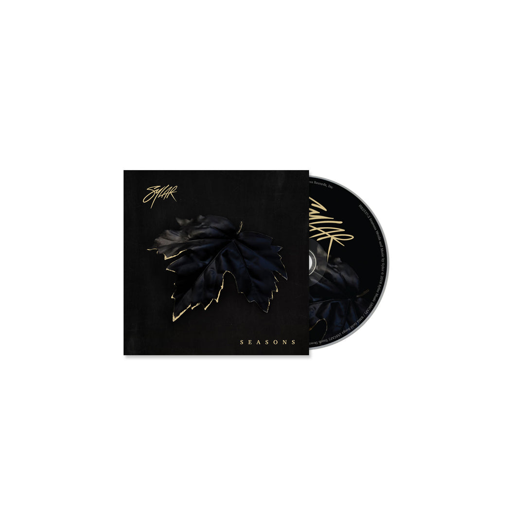 The Sylar CD and case have a black background with a dark, gold-outlined leaf in the center. SEASONS, inspired by tracks like Open Wounds, and Sylar’s stylized signature are displayed in shimmering gold lettering.