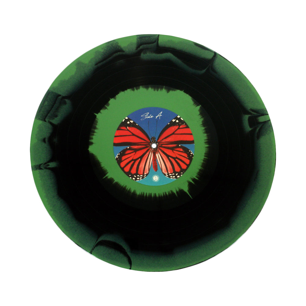 A limited edition Between You And Me vinyl with a green and black border. The center label displays a red butterfly with white and black markings on a blue-green background—a must-have for collectors who know butterflies change everything.