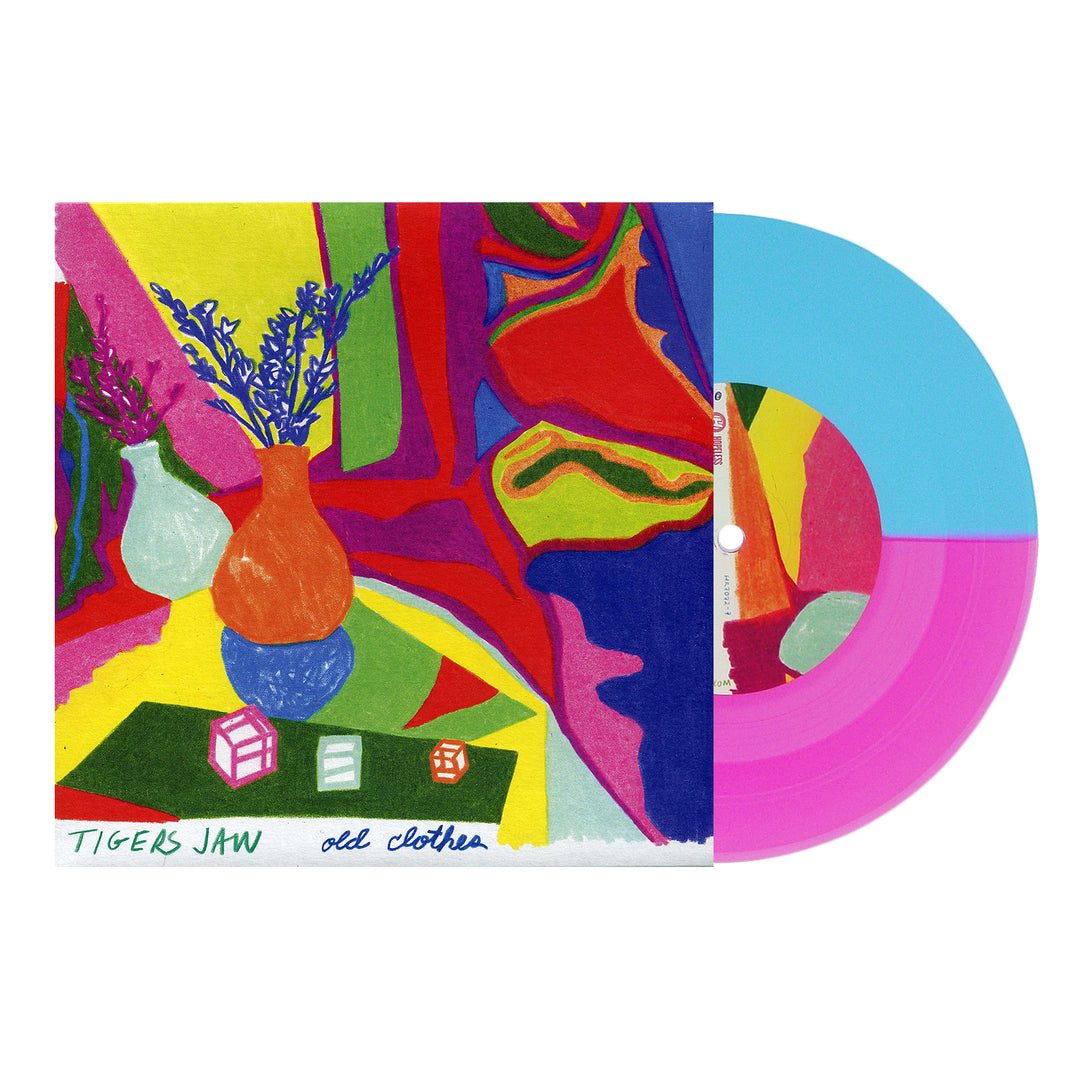 A vibrant album cover with abstract shapes, a vase of purple flowers, and two dice displays a half-blue, half-neon magenta vinyl partially inside. The text includes Tigers Jaw, old clothes, and the tracklist at the bottom. Brand: Tigers Jaw.