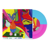 A vibrant album cover with abstract shapes, a vase of purple flowers, and two dice displays a half-blue, half-neon magenta vinyl partially inside. The text includes Tigers Jaw, old clothes, and the tracklist at the bottom. Brand: Tigers Jaw.