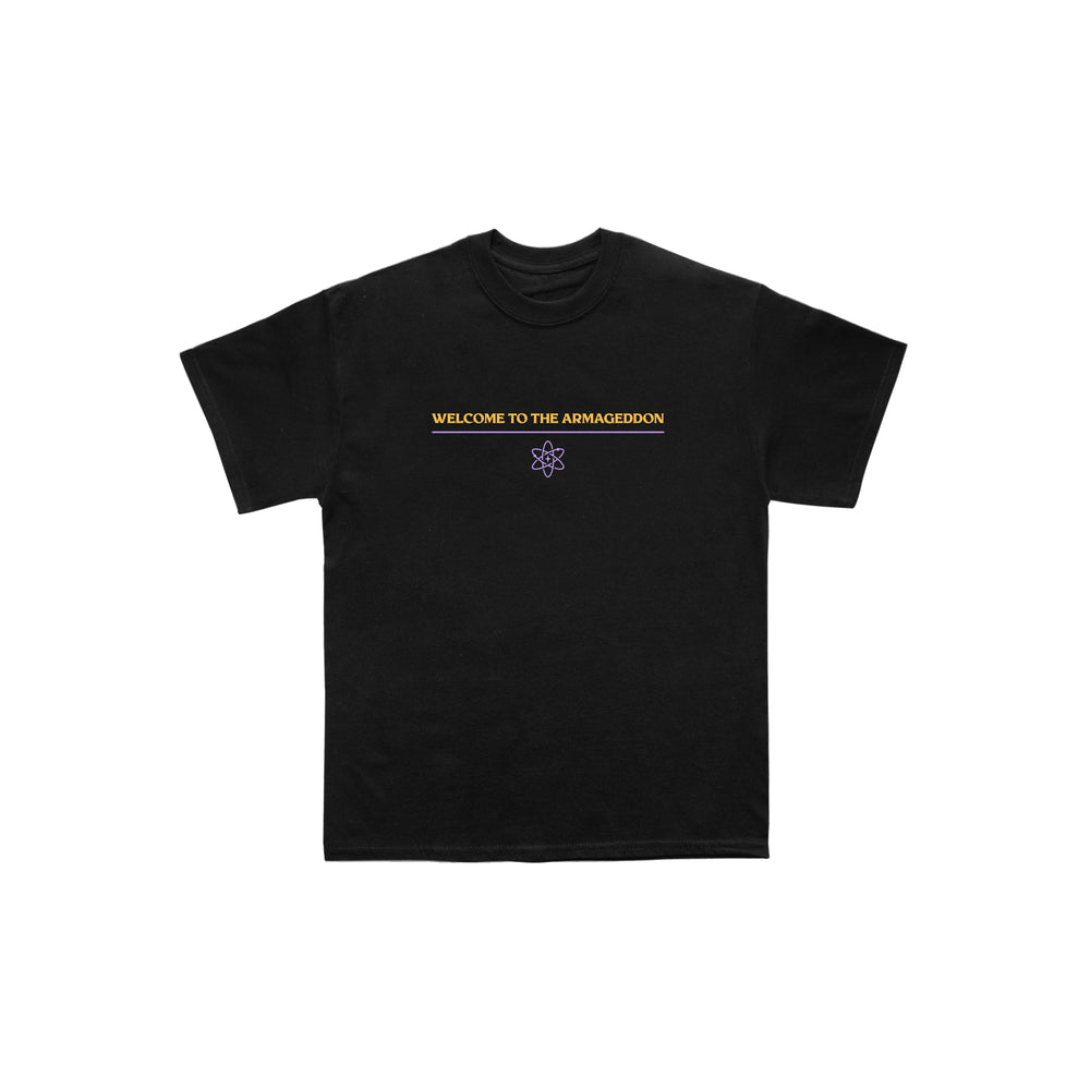 Exclusive Between You And Me design on a black Next Level tee: WELCOME TO THE ARMAGEDDON in yellow, centered above a small purple atom graphic. Plain white background.