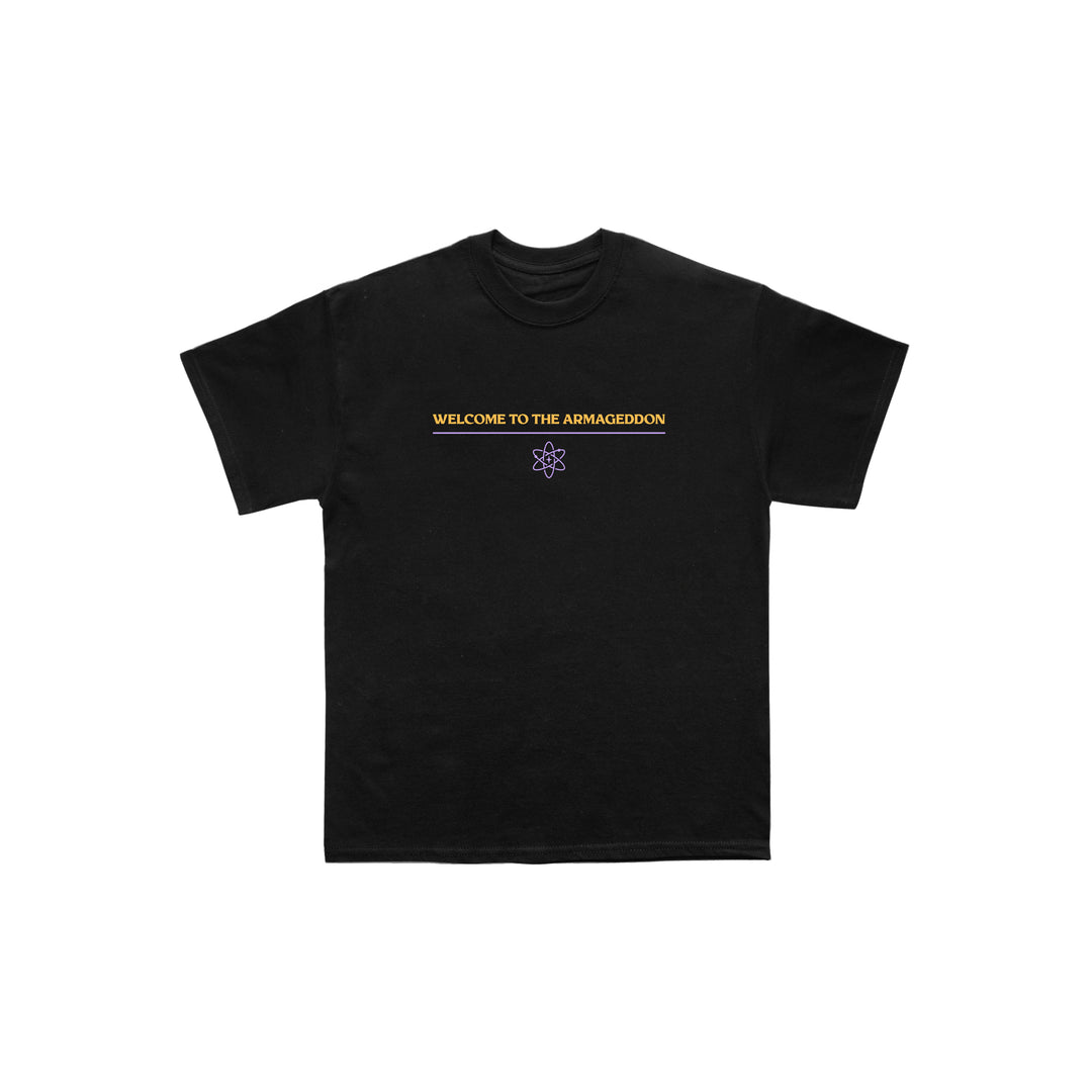 Exclusive Between You And Me design on a black Next Level tee: WELCOME TO THE ARMAGEDDON in yellow, centered above a small purple atom graphic. Plain white background.