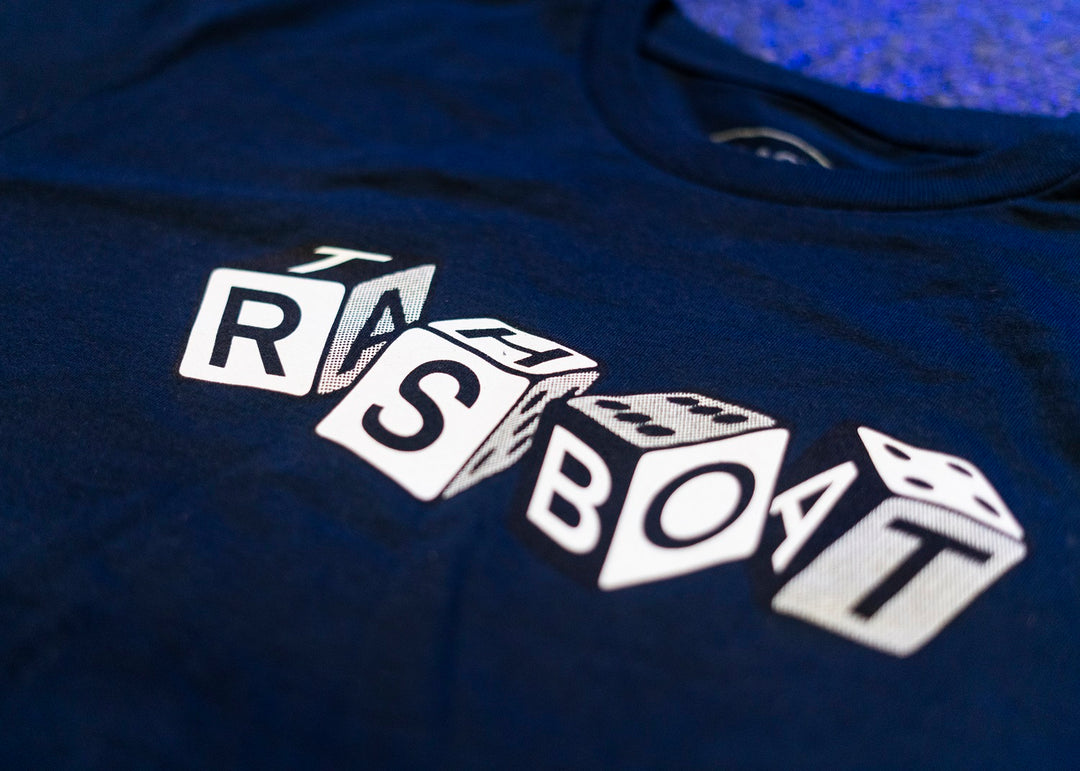 Trash Boat navy T-shirt with a graphic of five overlapping white dice spelling “TRSBOAT.” This stylish Band Merch is a must-have for any Trash Boat fan.