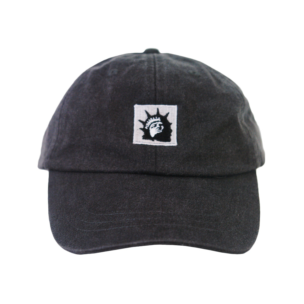 A black dad hat by Trophy Eyes with a white square patch featuring a black Statue of Liberty head graphic—ideal for anyone seeking a unique, classic statue hat.