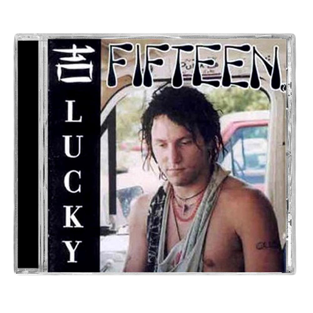 The CD cover for Lucky by Fifteen features a shirtless person with necklaces and messy hair in a vehicle with an open window, a blue car behind—capturing raw emotion and Family Values. Brand Name: Fifteen.