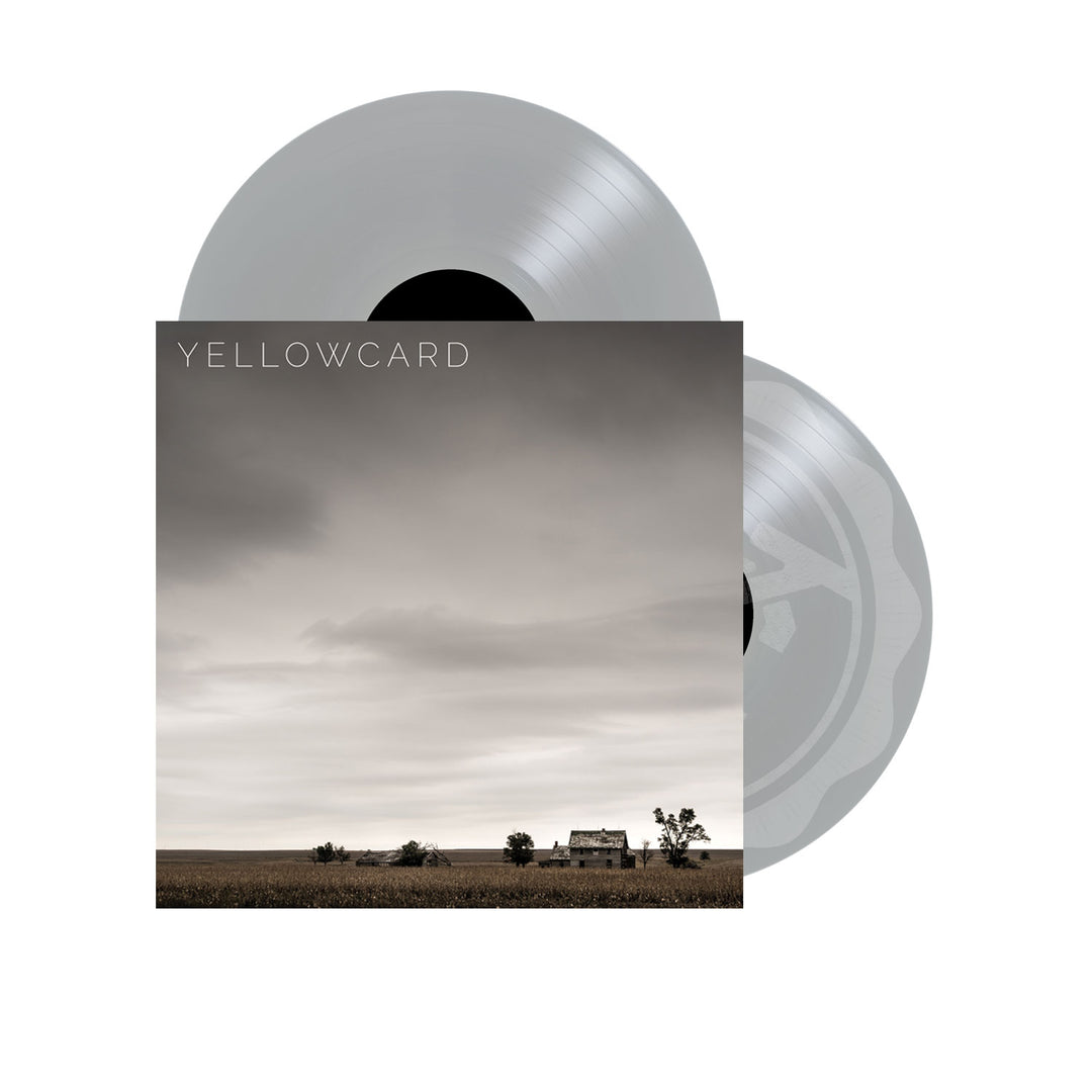 A vinyl album cover features a cloudy sky above a rural landscape with a barn and trees. Yellowcard’s name appears at the top, while two transparent silver vinyl records are partially visible behind the cover. Brand Name: Yellowcard.