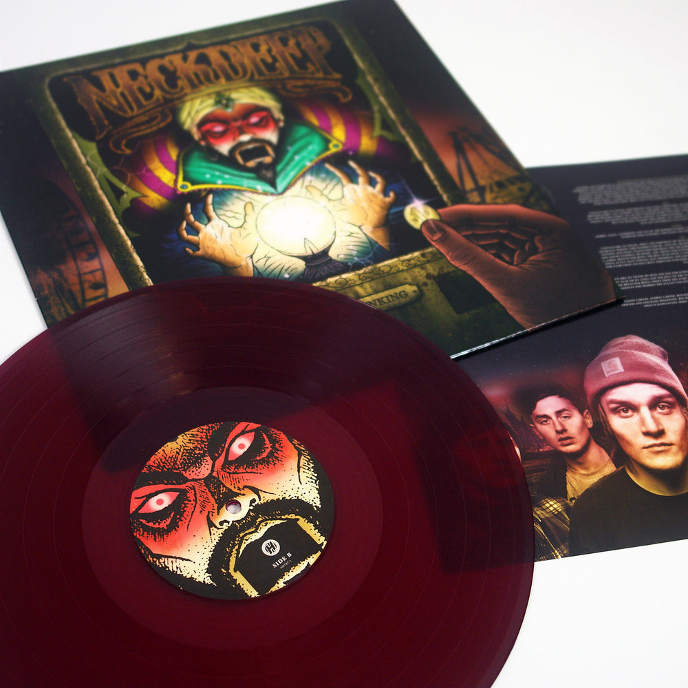 A translucent purple vinyl from Neck Deep sits before an album cover of a mystical figure holding a glowing crystal ball, with an insert displaying the tracklist and two men in beanies partially visible beside the record.