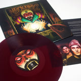 A translucent purple vinyl from Neck Deep sits before an album cover of a mystical figure holding a glowing crystal ball, with an insert displaying the tracklist and two men in beanies partially visible beside the record.