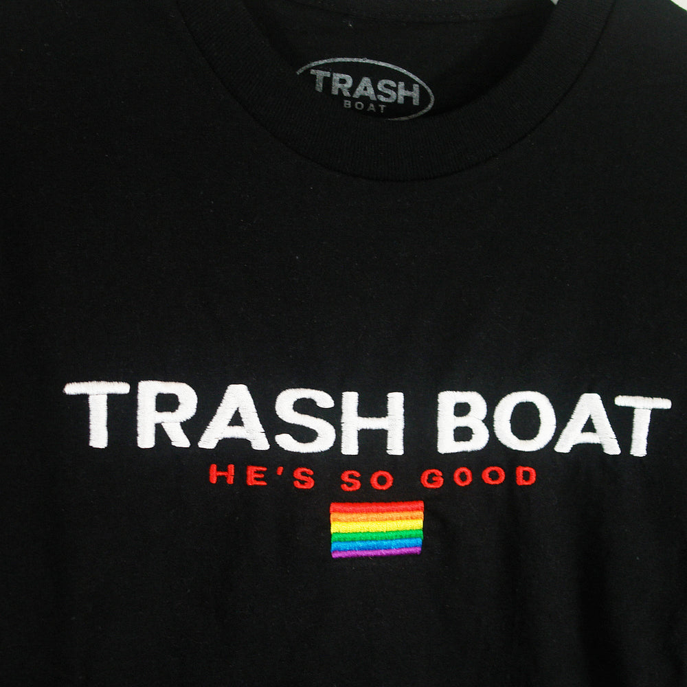 Trash Boat black shirt with white TRASH BOAT text, red HE’S SO GOOD, and a small rainbow pride flag patch. Available in sizes up to X-Large.